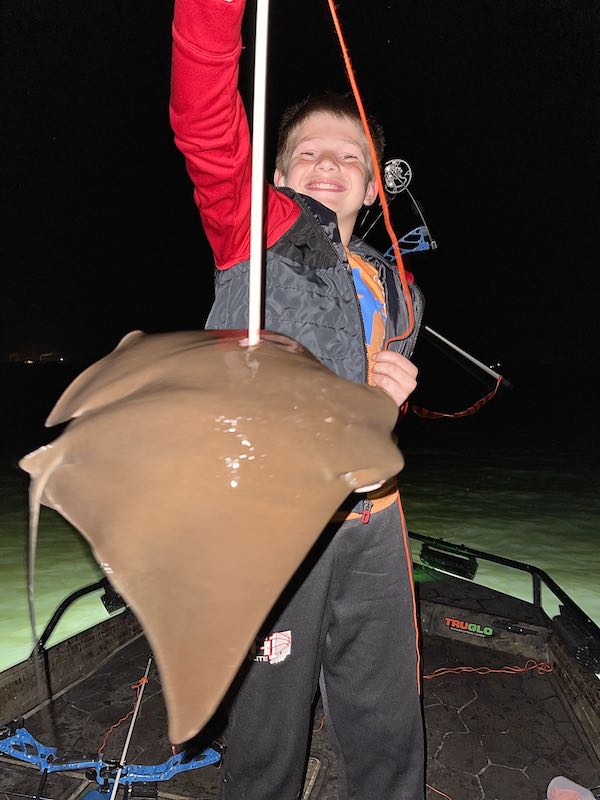 Child  holding a large stingray he shot at night on a bowfishing charter in Florida. 