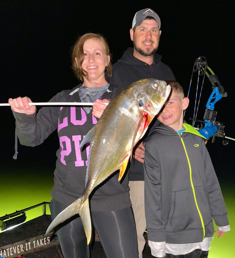 Family holding a large fish at night on a Florida Bowfishing Charter. 