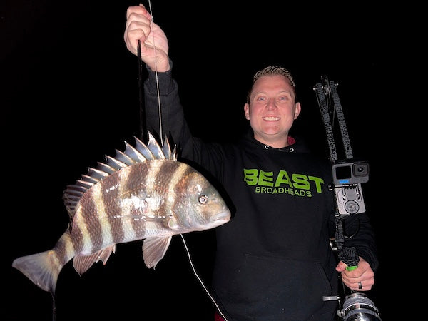 Man holding a sheepshead and a bowfishing bow with a 'Beast Broadheads' logo on a dark background